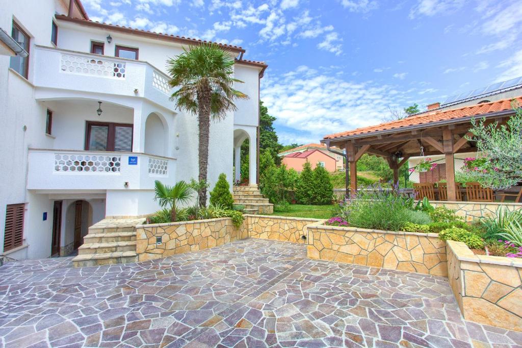 a home with a stone walkway in front of a house at Apartments Stolfa in Krk
