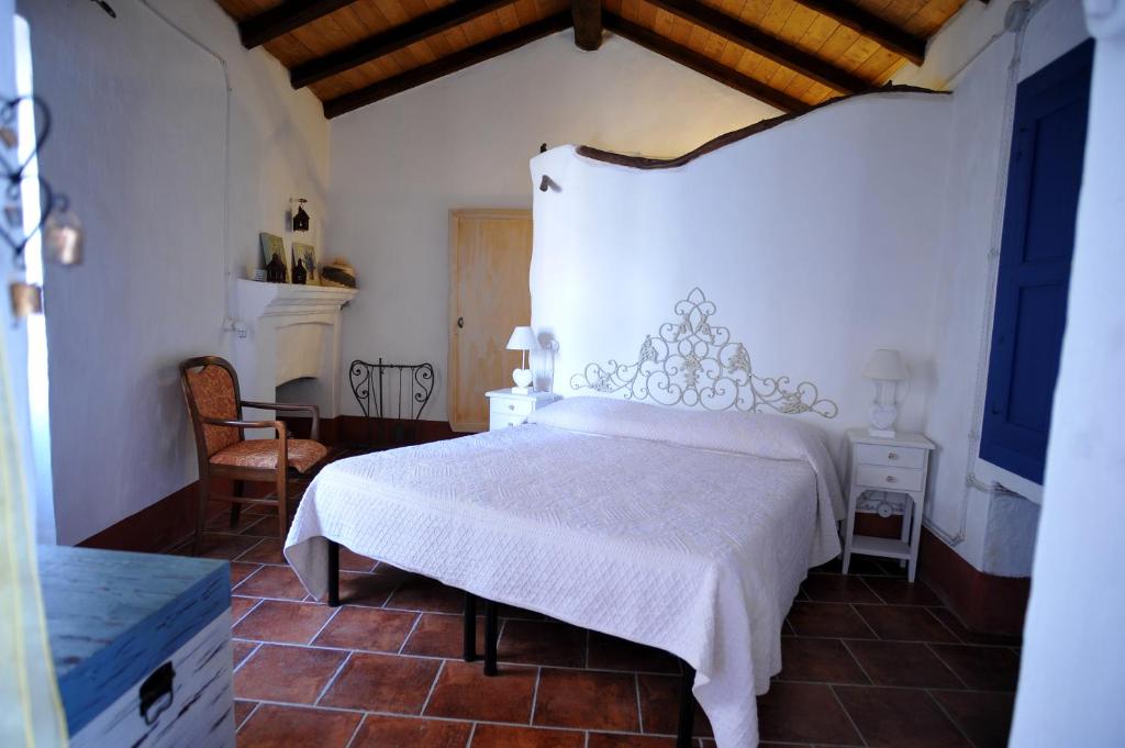 a bedroom with a white bed and a chair at B&B Corte San Lussorio in Oliena
