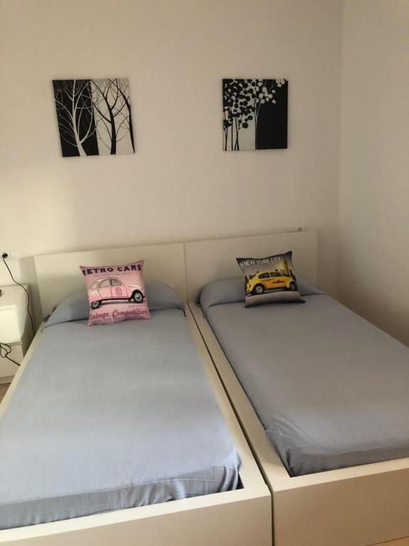 2 łóżka pojedyncze w pokoju z obrazami na ścianie w obiekcie apto Fradera w mieście La Savina