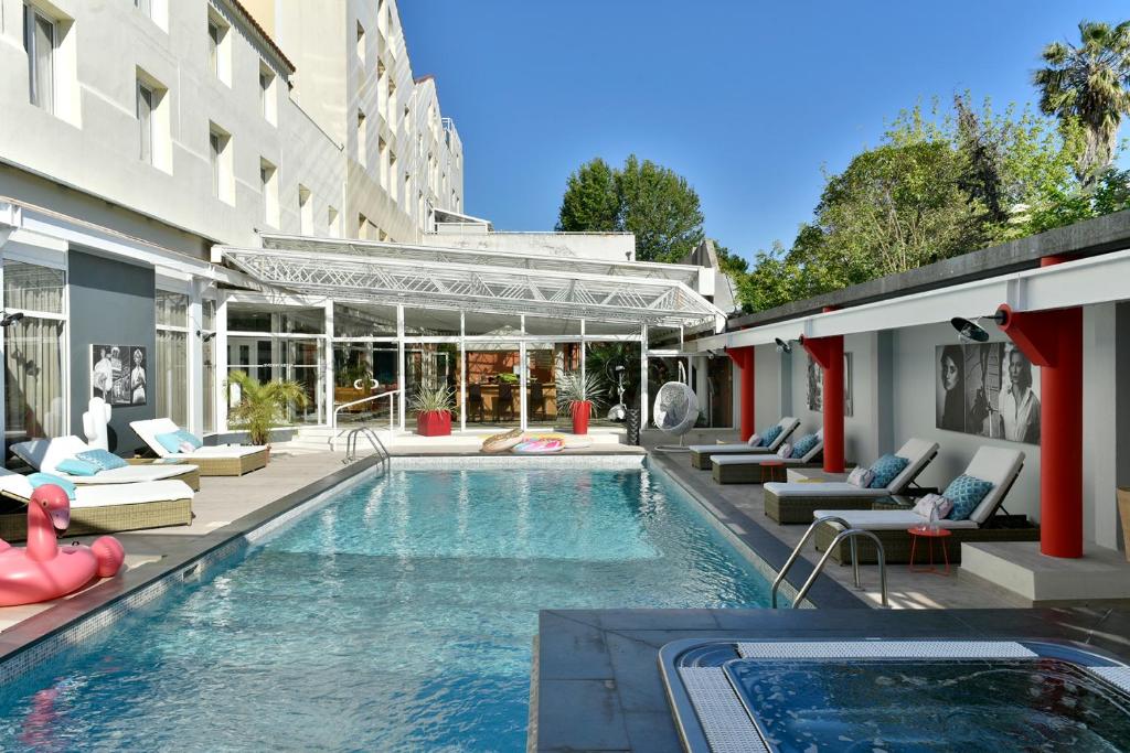 a swimming pool with lounge chairs and a building at Hôtel Arles Plaza in Arles