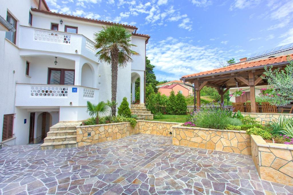 a home with a stone walkway in front of a house at Rooms Stolfa in Krk