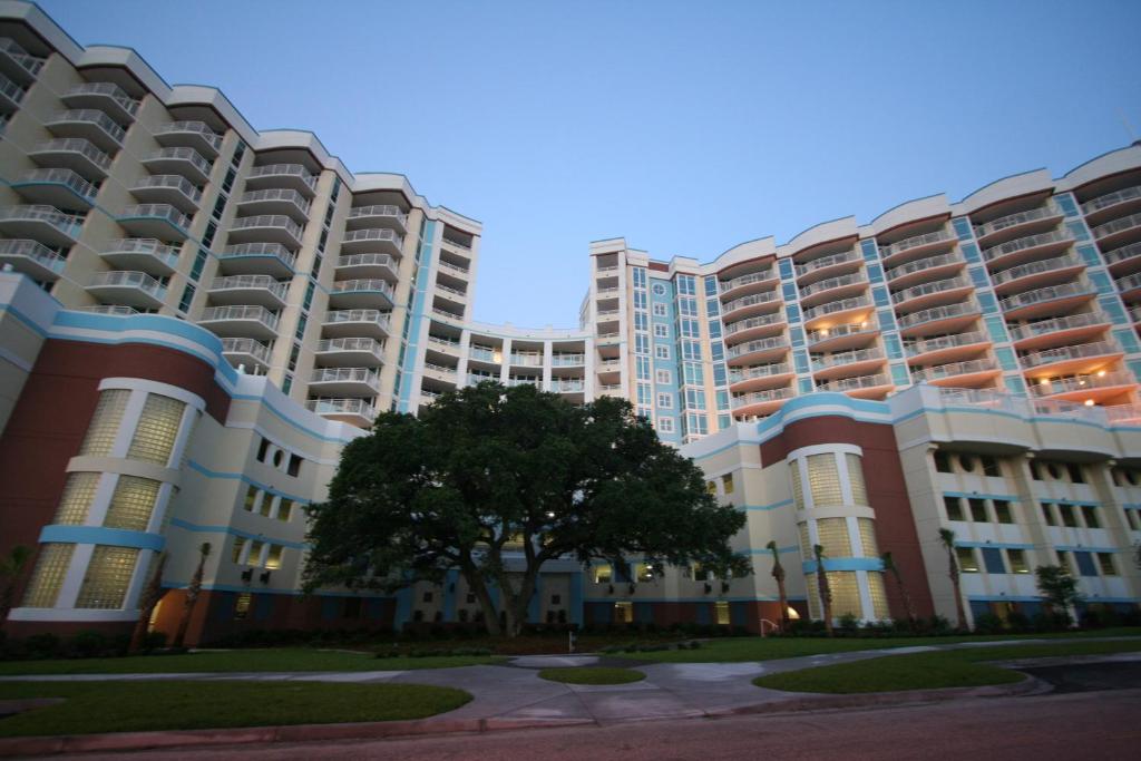 a large apartment building with a tree in front of it at The Horizon at 77th in Myrtle Beach