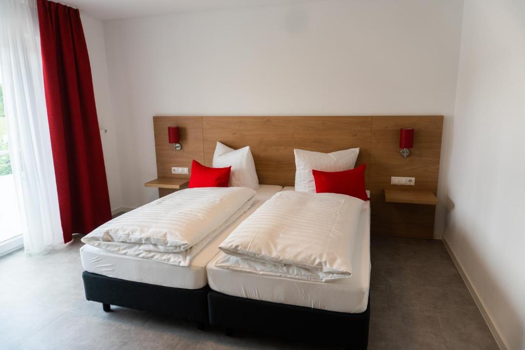 a bedroom with two beds with red pillows at Pension Haas-Hotel am Turm in Rottweil
