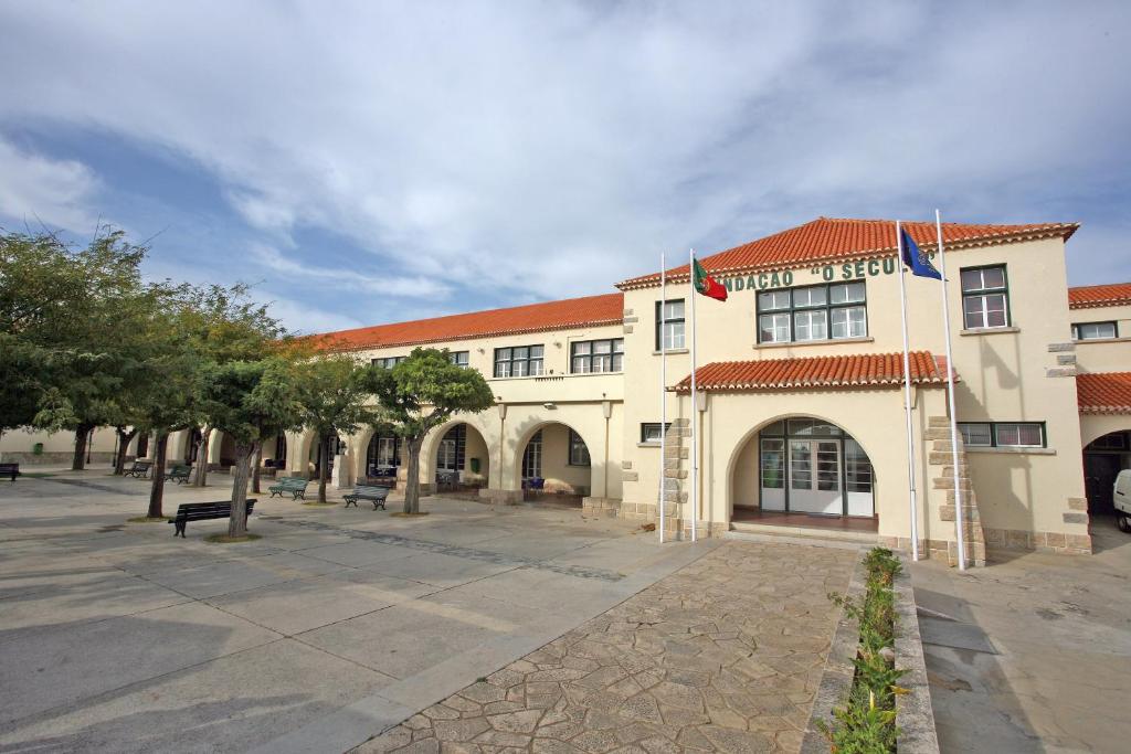 un grand bâtiment avec deux drapeaux devant lui dans l'établissement Turismo do Seculo, à Estoril