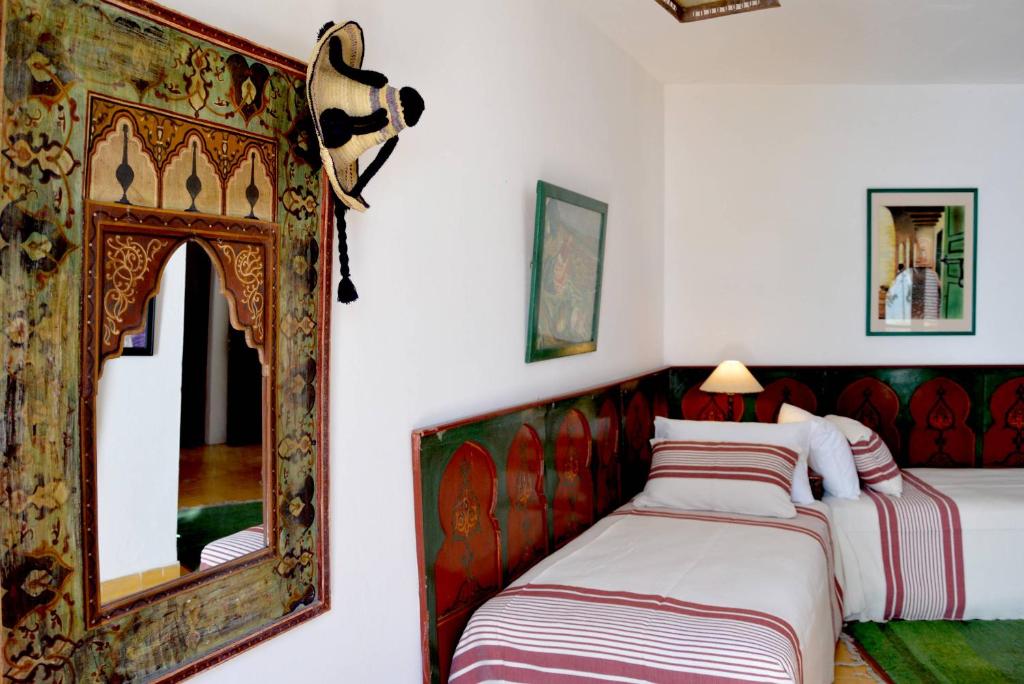 a bedroom with two beds and a mirror at RIAD OASIS D'ASILAH in Asilah