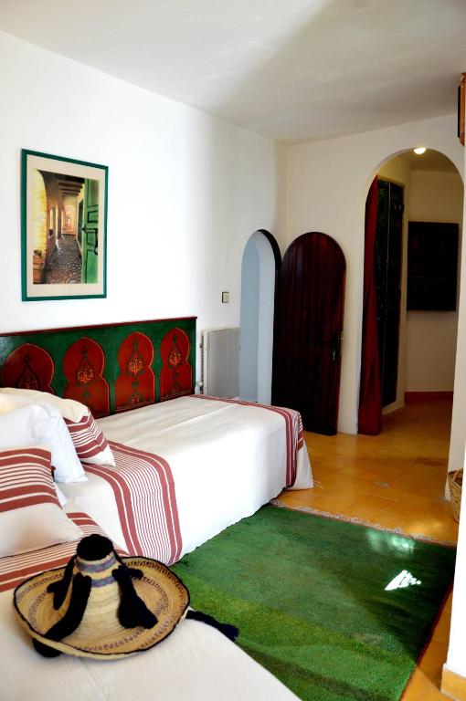 a hotel room with two beds and a hat on the bed at RIAD OASIS D'ASILAH in Asilah