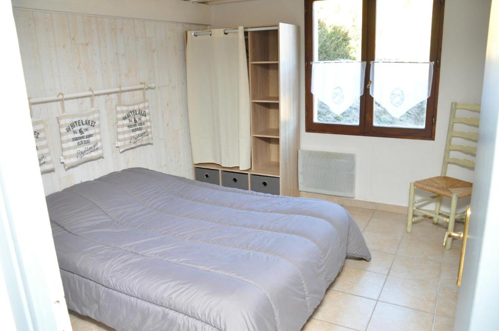 a bedroom with a bed and a window and a chair at gite les iris in La Robine