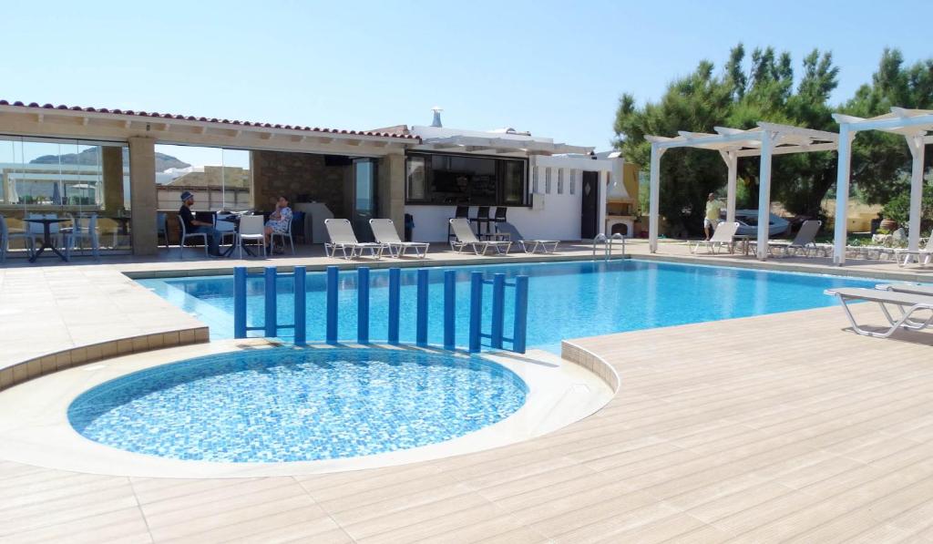 a large swimming pool with a wooden deck next to a house at Captain's Beach Apartments in Kissamos