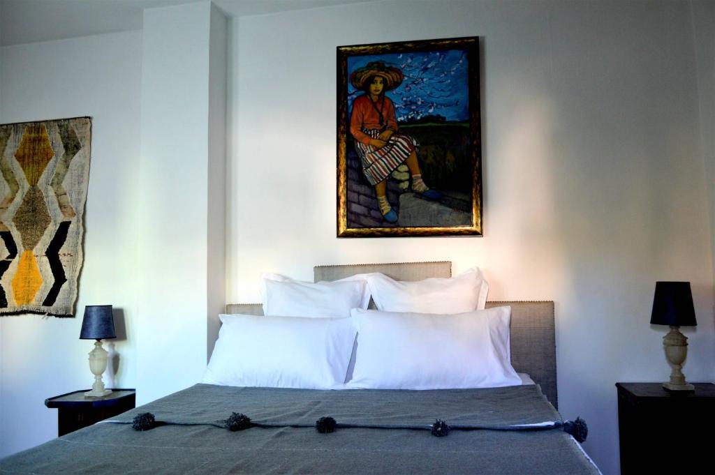 a bedroom with a bed with a painting on the wall at RIAD OASIS D'ASILAH in Asilah