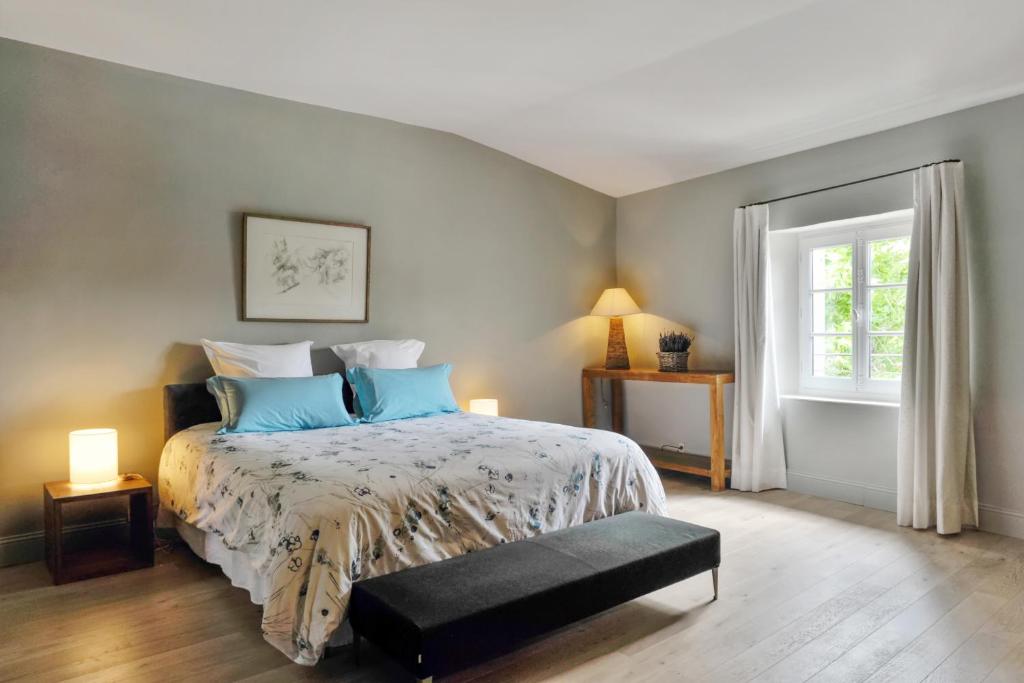 a bedroom with a bed with blue pillows and a window at Maison Hache in Eygalières