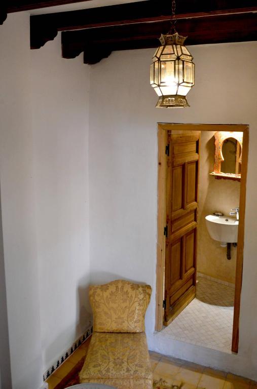 a bathroom with a chair and a sink and a chandelier at RIAD OASIS D'ASILAH in Asilah