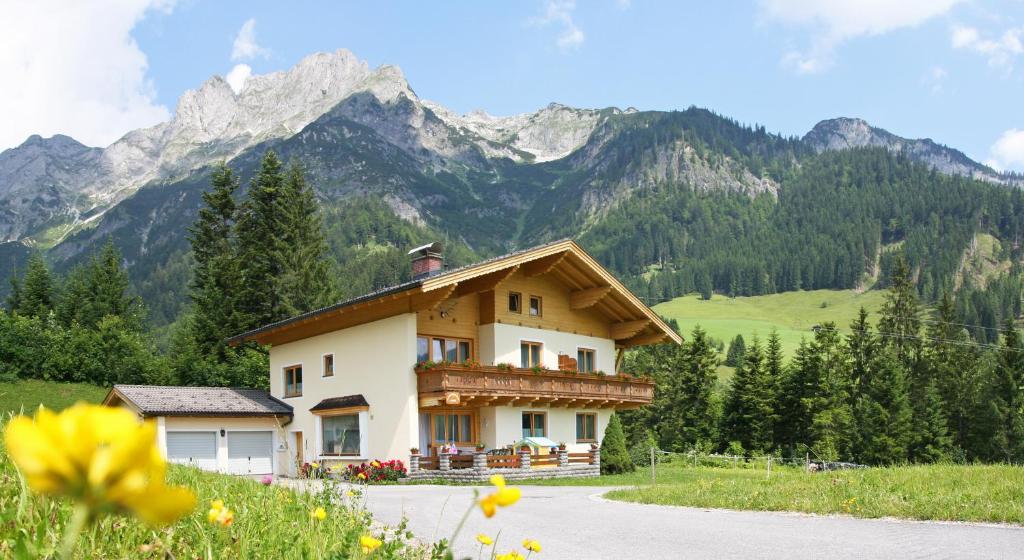 a house on a hill with mountains in the background at Apartments Alpenfrieden in Sankt Martin am Tennengebirge