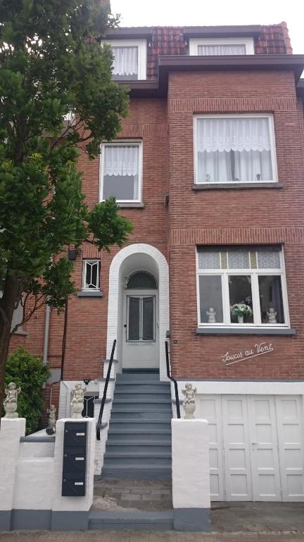 ein Backsteinhaus mit einer weißen Tür und einer Treppe in der Unterkunft Soucis au vent in De Panne