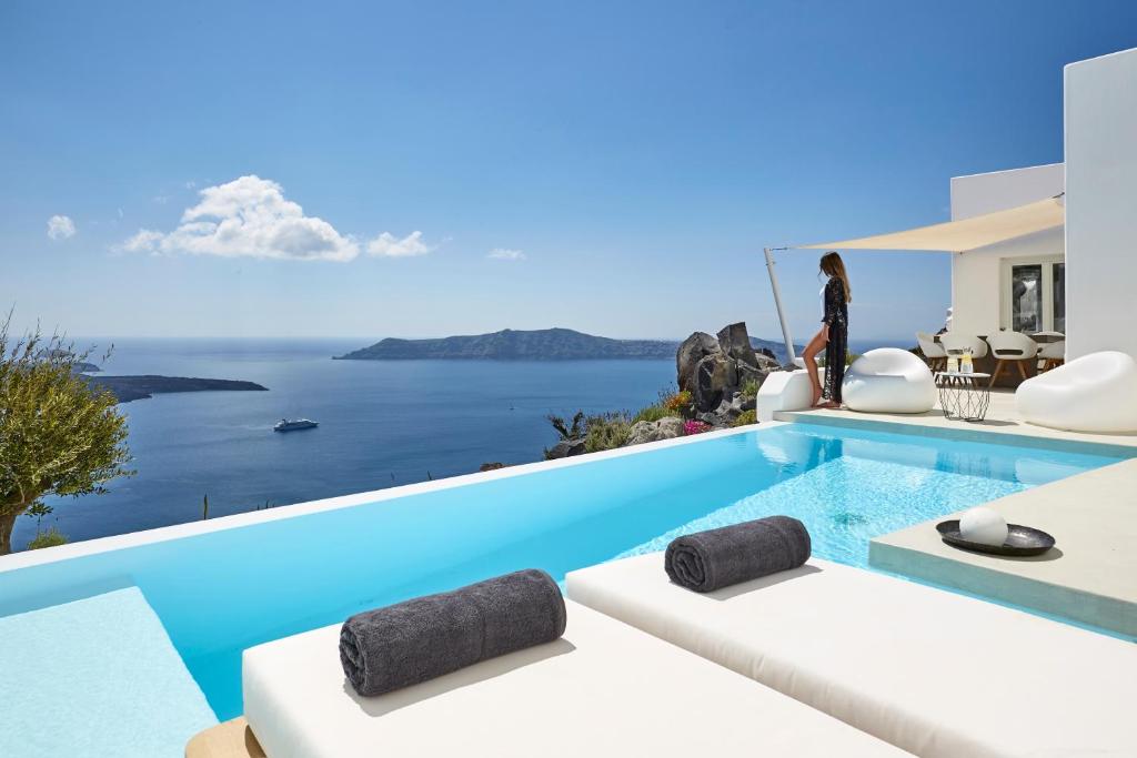 a villa with a swimming pool with a view of the ocean at Villa Etheras in Firostefani