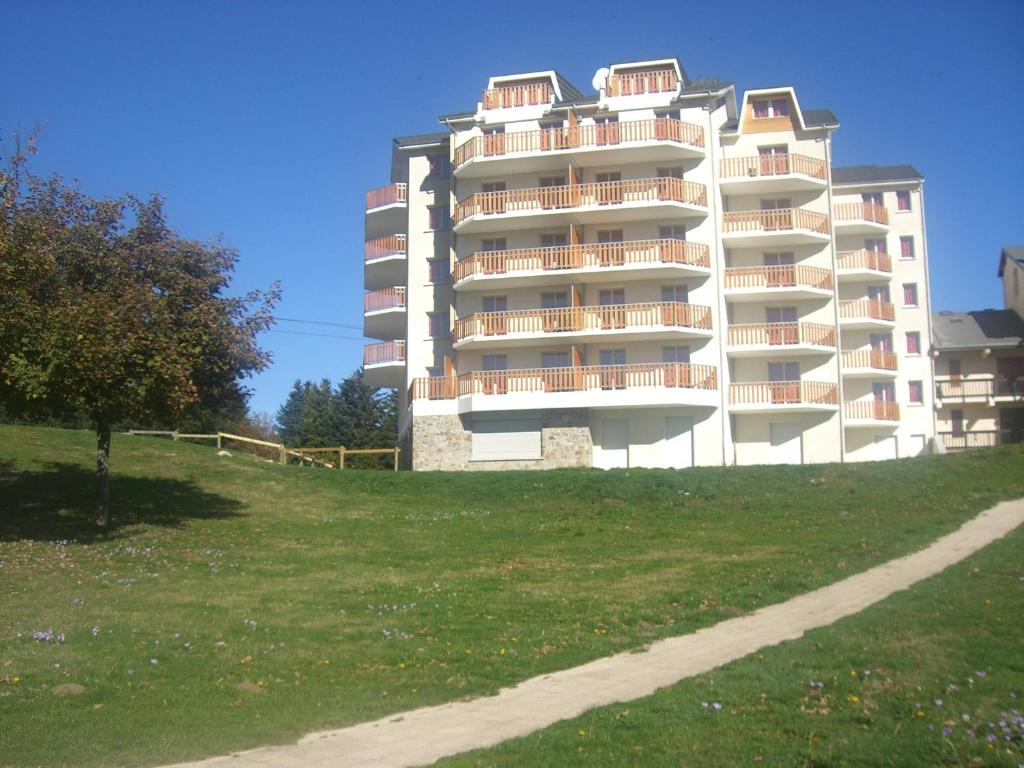 ein großes weißes Apartmenthaus auf einem grasbewachsenen Hügel in der Unterkunft Résidence Néméa Les Balcons d'Ax in Ax-les-Thermes
