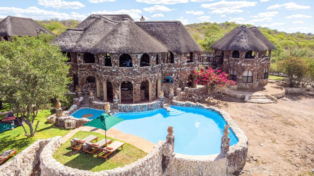 an old house with a swimming pool in front of it at Eagle Tented Lodge & Spa in Okaukuejo