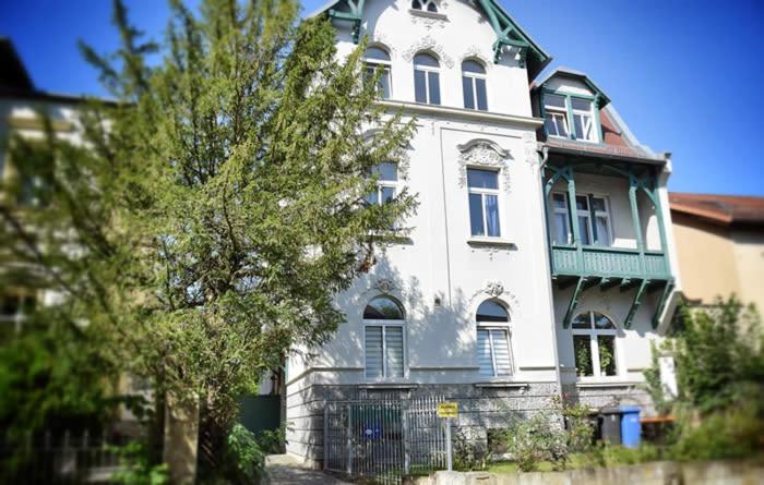 ein großes weißes Haus mit einem Zaun davor in der Unterkunft Kunterbunt in Naumburg