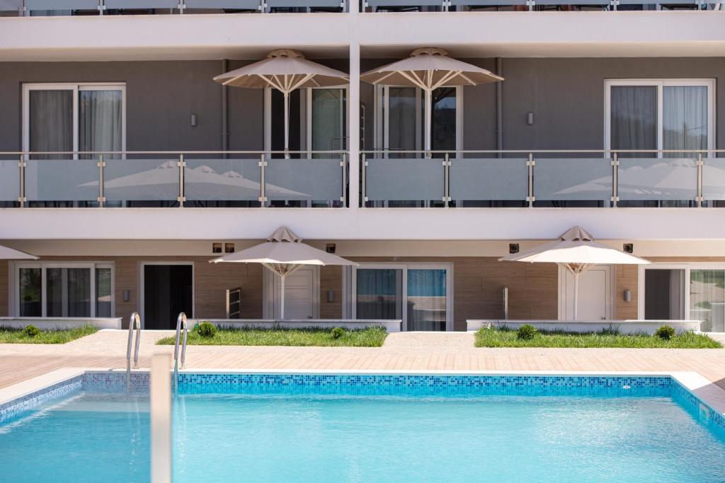 a hotel with a swimming pool and umbrellas at Astra Sarti Luxury Suites in Sarti