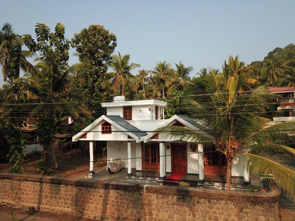 una casa blanca en la parte superior de una pared de ladrillo en Belhaven Home Stay en Thiruvananthapuram