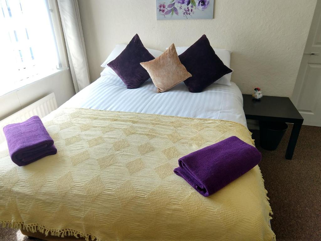 a bedroom with a bed with purple pillows on it at Rowe Gardens - Self Catering - Guesthouse Style - Comfortable Twin or Double Rooms - Quiet Residential Area in Workington