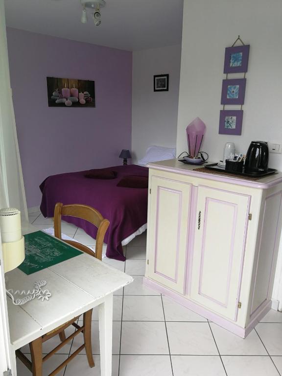 - une chambre avec un lit violet et une table dans l'établissement Auberge du Vieux Tour, à Canapville