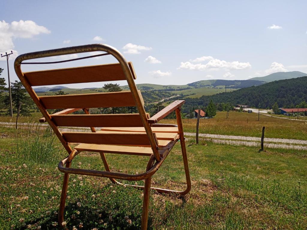 a wooden chair sitting in the grass in a field at Planinarski dom "Tornik" Zlatibor in Ribnica