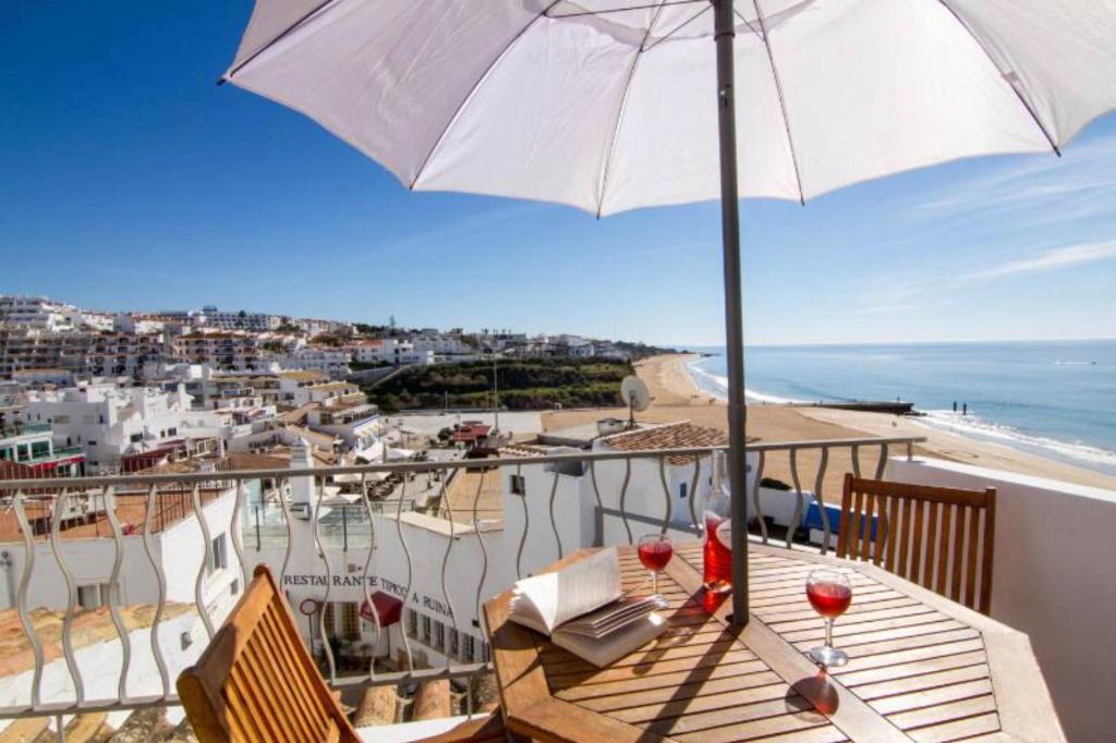 a balcony with an umbrella and a table with wine glasses at Casa T'Isabel - Fisherman's Beach - 2 bedrooms in Albufeira