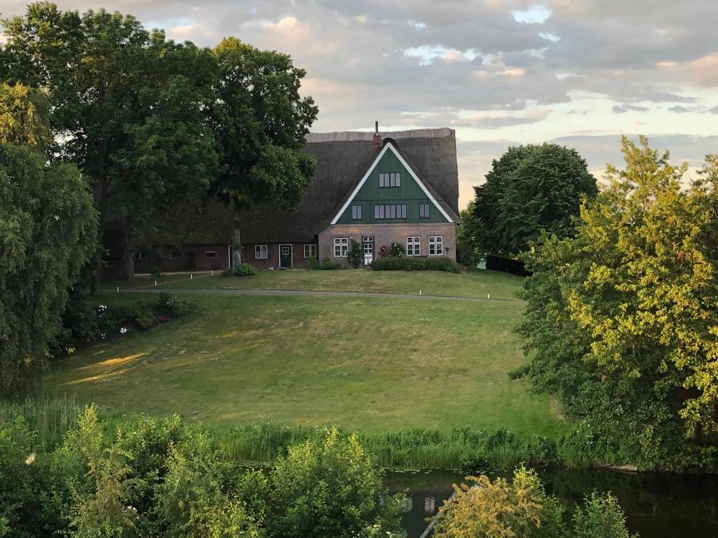 ein großes Haus mit grünem Dach auf einem Grasfeld in der Unterkunft Gut Bielenberg in Kollmar