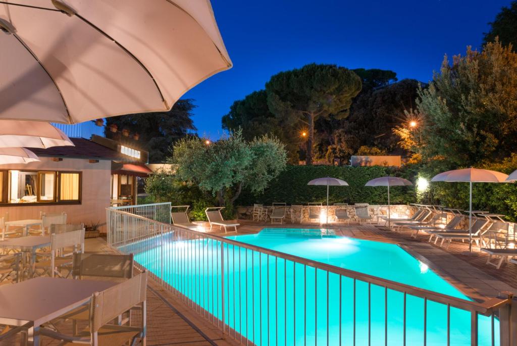 a swimming pool with chairs and umbrellas at night at Duca Del Mare - Hotel Di Nardo group in Massa Marittima