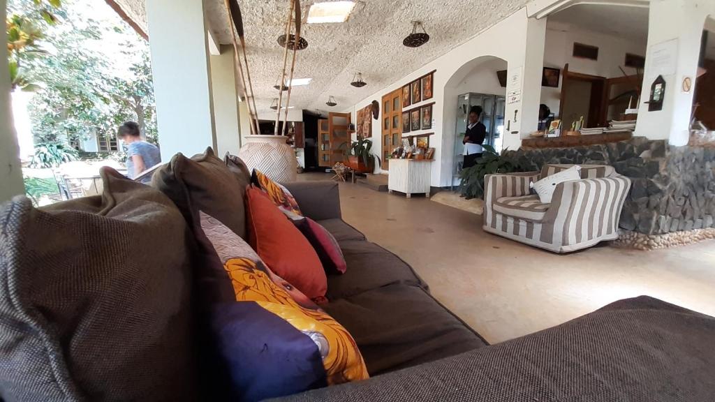 a living room with a brown couch with colorful pillows at Gately Inn Entebbe in Entebbe