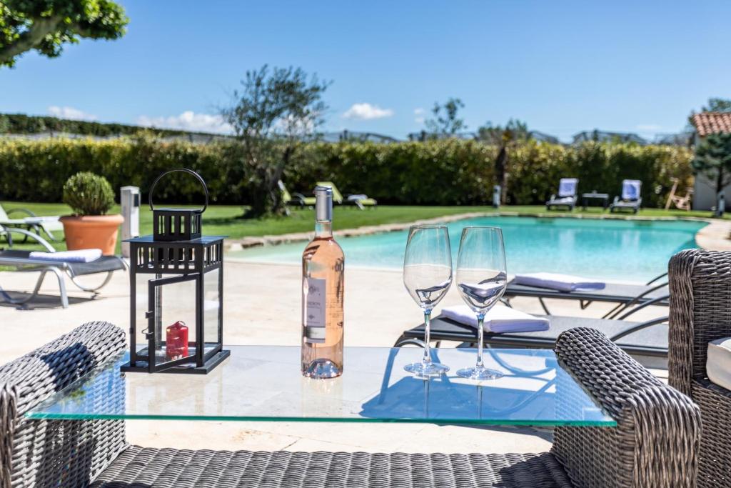 - une table en verre avec une bouteille de vin et 2 verres dans l'établissement Mas Saint Julien, à Cavaillon