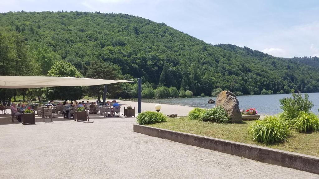 a group of people sitting at tables near a lake at Hôtel Domaine du Lac Chambon in Murol