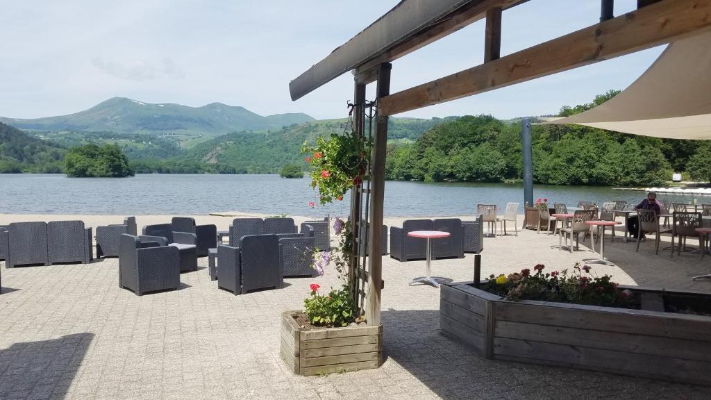 a patio with chairs and tables and a view of a lake at Hôtel Domaine du Lac Chambon in Murol