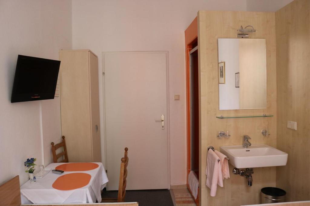 Zimmer mit einem Bad mit einem Waschbecken und einem Spiegel in der Unterkunft Pension Reimer in Wien