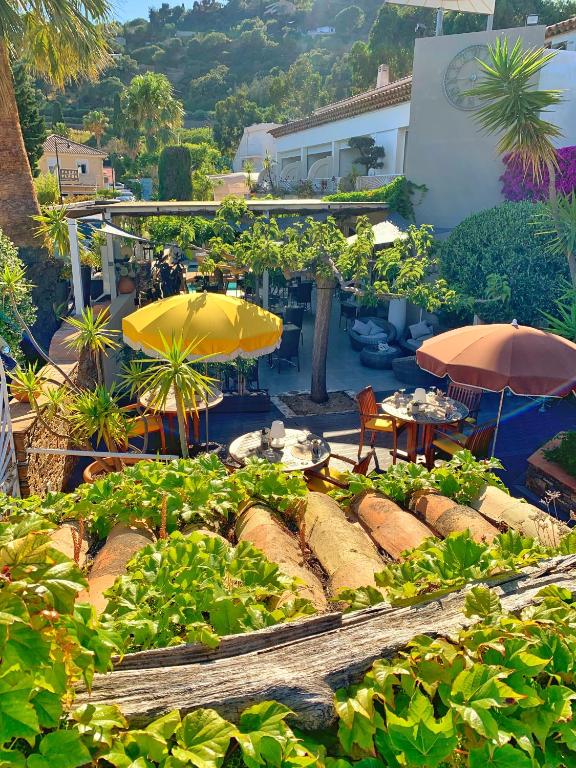 a garden with umbrellas and tables and chairs at Hôtel Beau Soleil in Le Lavandou