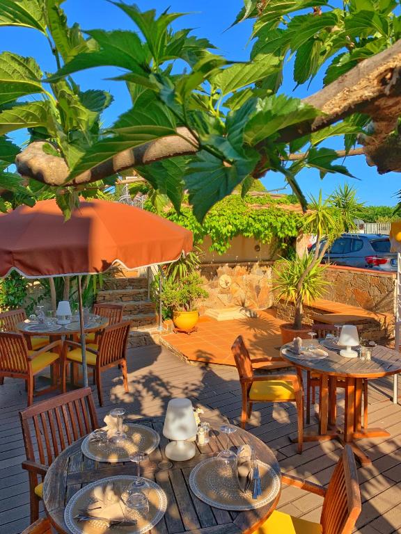 a patio with tables and chairs and an umbrella at Hôtel Beau Soleil in Le Lavandou
