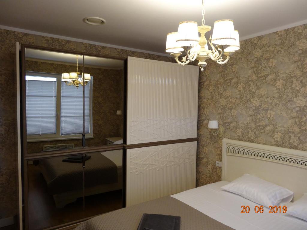 a bedroom with a bed and a chandelier at JURMALA APARTMENT in Jūrmala