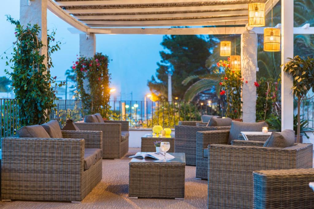a group of wicker chairs and tables on a patio at Boutique Hotel Oriola in Cala de Sant Vicenc