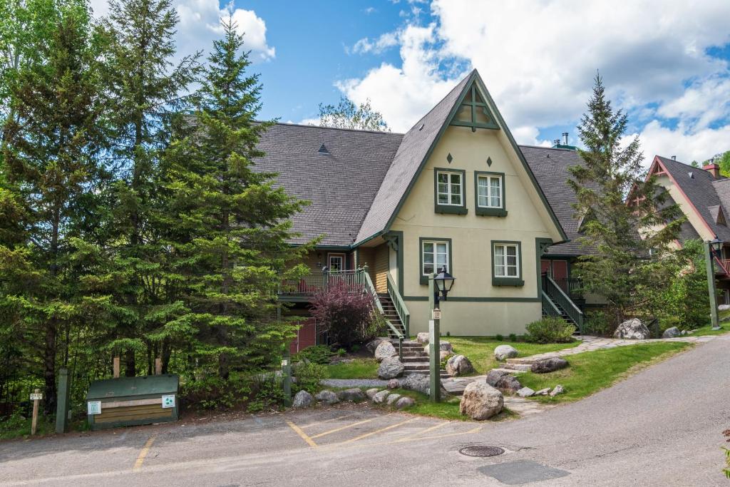 ein gelbes Haus mit einem Gameradach in der Unterkunft Le Plateau by Rendez-Vous Mont-Tremblant in Mont-Tremblant