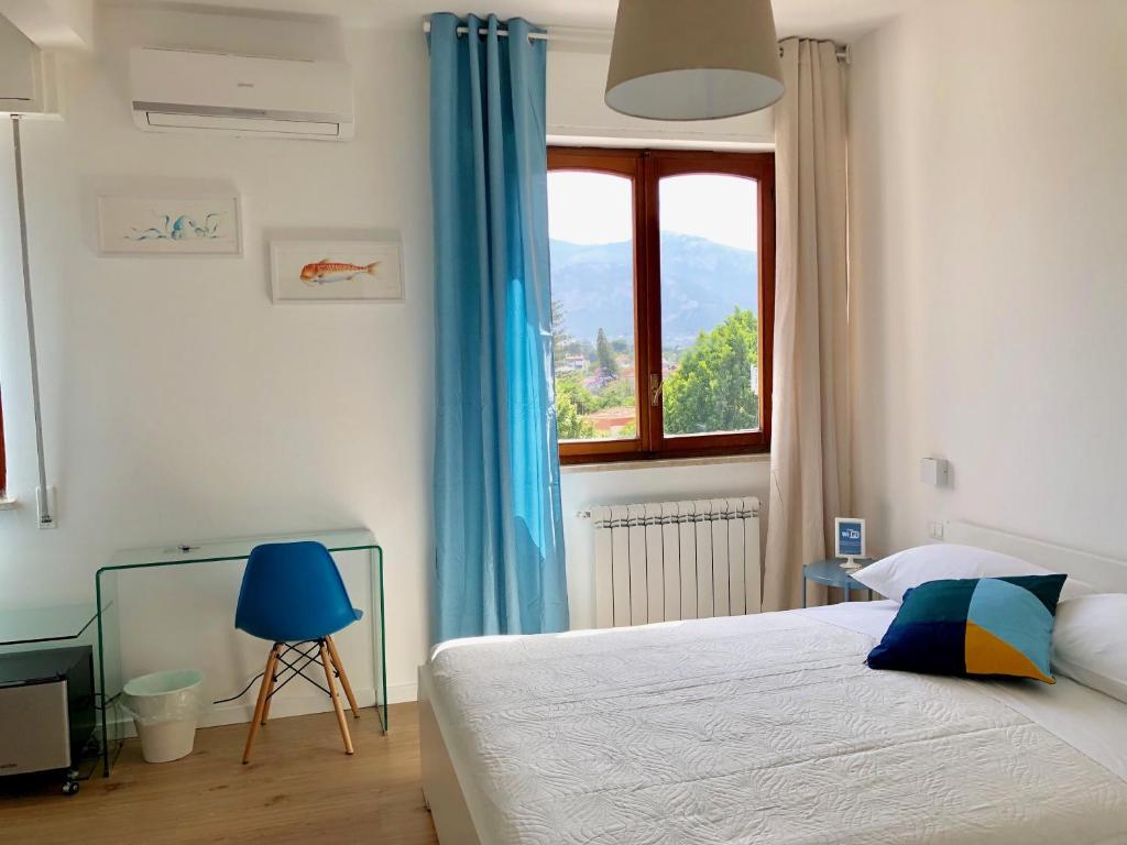 - une chambre avec un lit doté de rideaux bleus et d'une fenêtre dans l'établissement Mondello Beach - Rooms By The Sea, à Mondello