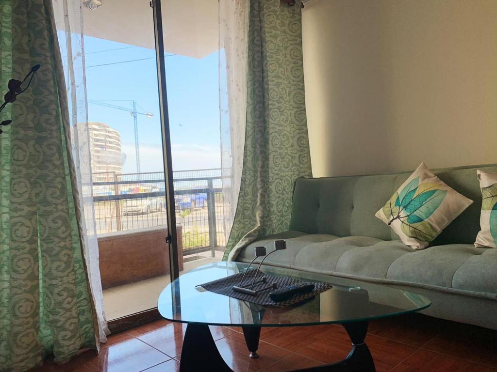 a living room with a couch and a glass table at Grato Departamento frente a la playa, con Jacuzzi in Arica