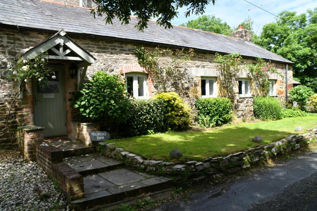 una antigua casa de piedra con una puerta verde en TREWASSICK BARN en Newquay