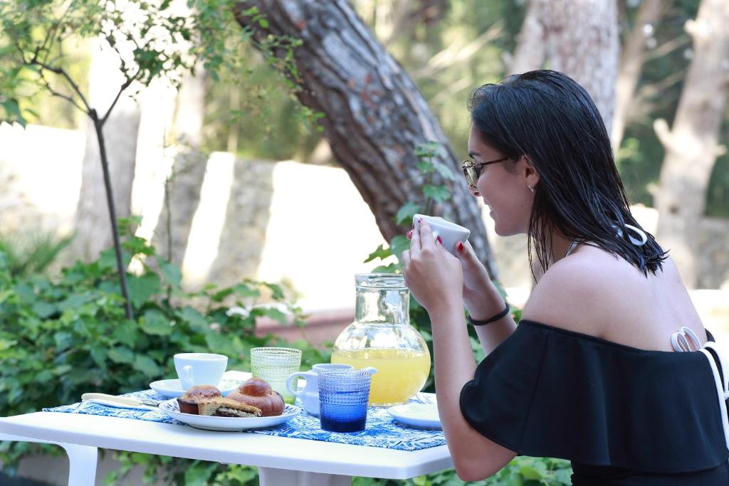 a woman taking a picture of a table with a plate of food at Dimora Villa Serena Porto Selvaggio in Santa Caterina di Nardò
