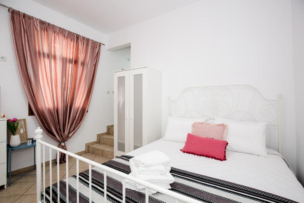 um quarto com uma cama branca e uma almofada vermelha em Anastasia’s House em Kissamos