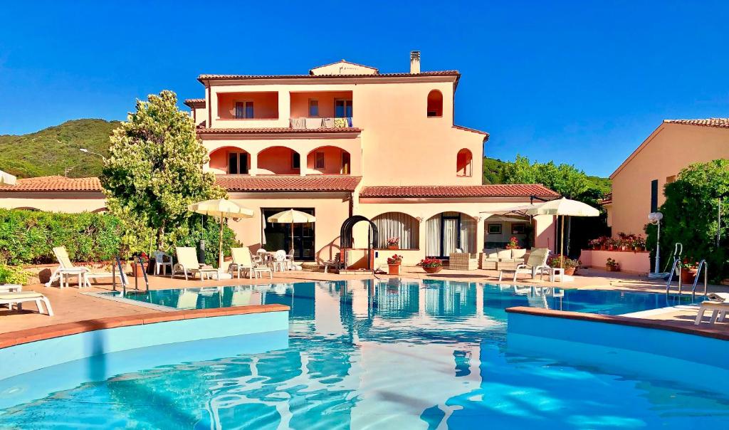 a villa with a swimming pool in front of a house at Arthotel Gabbiano Azzurro Due in Marciana Marina