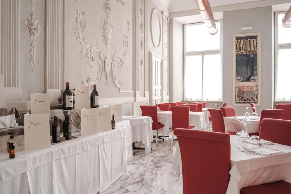 a dining room with white tables and red chairs at Hotel De Ville in Genoa