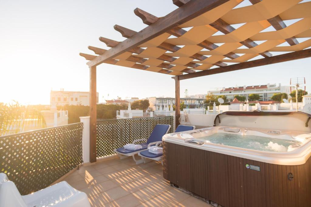 bañera de hidromasaje en una terraza con pérgola en Villa Ria Rose, Alto da Ria 23 - jacuzzi and beach, en Alvor