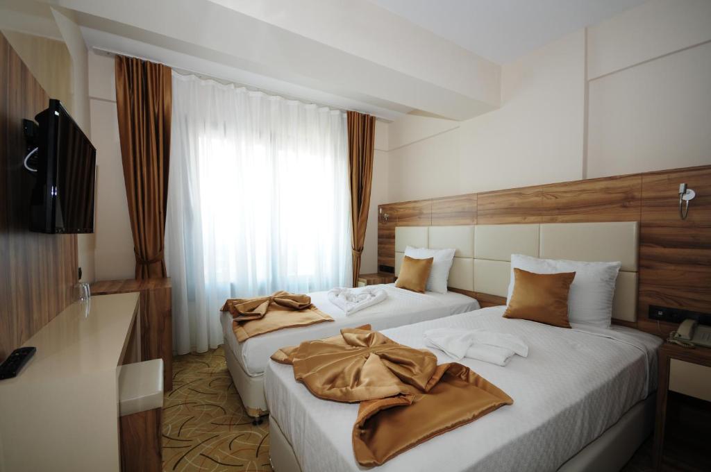 um quarto de hotel com duas camas e uma televisão em Grand Hekimoğlu HOTELS em Izmir
