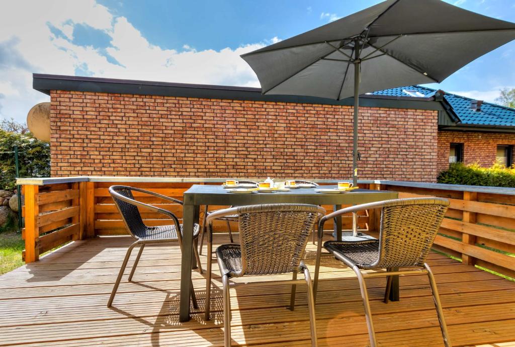 a table and chairs with an umbrella on a deck at Ferienwohnungen am Peenehafen Karl in Ostseebad Karlshagen