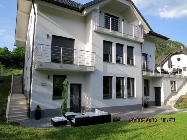 una grande casa bianca con portico e balcone di Sunlight Apartment a Bled